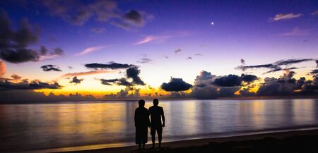 family man and woman on the ocean greet the dawnの写真素材
