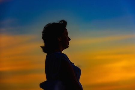 silhouette of a woman meets sunrise on the beach background palm treesの写真素材