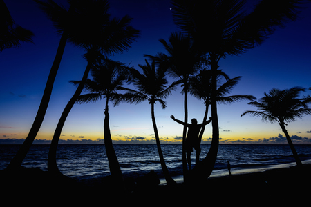 a man among palm trees meet a beautiful sunrise on the ocean shoreの写真素材