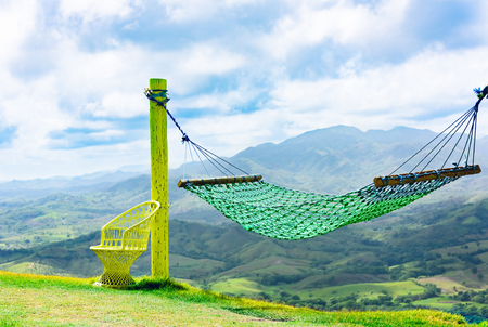 green hammock hanging between the pillars on the hillsideの写真素材
