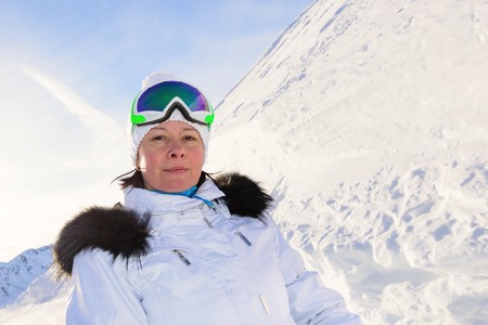 Woman skier in a white suit mountain top in snowの写真素材