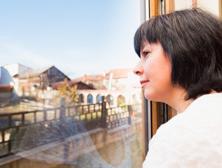 Brunette middle-aged woman is looking out the window
