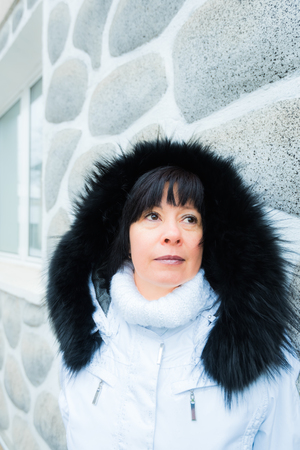 portrait of a middle-aged brunette in a white jacket with a hood on a background of mountainsの写真素材