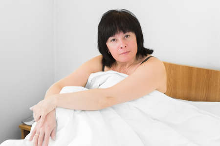 Brunette middle-aged woman lying in bed the morningの写真素材