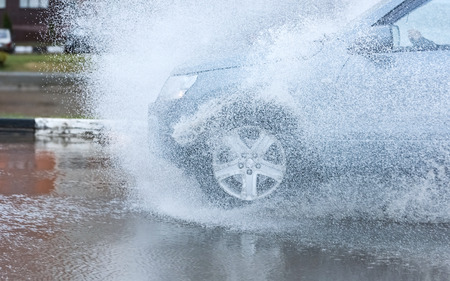 motion car rain big puddle of water spray from the wheelsの写真素材