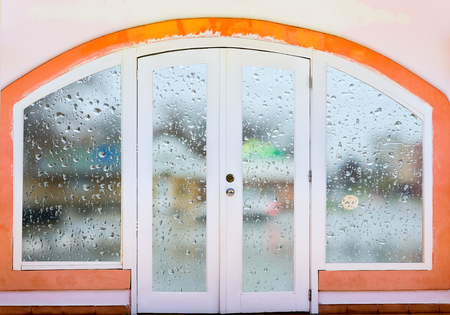 Closed door arch with curtains in rainy autumn weatherの写真素材