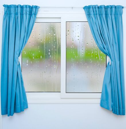 Closed window with curtains in rainy autumn weatherの写真素材
