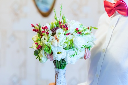 the groom in a blue suit holding a wedding bouquet of flowersの写真素材