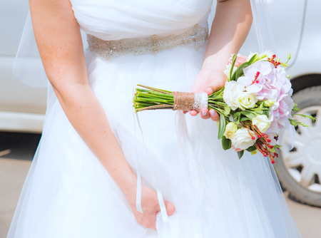 bride in a white dress holding a wedding bouquet of flowersの写真素材