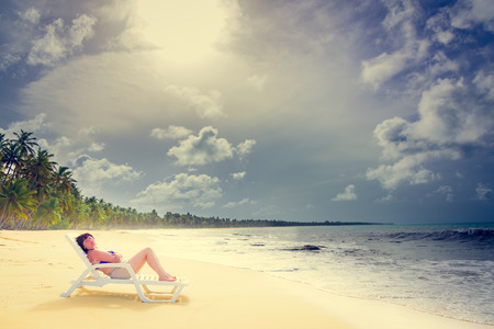 brown-haired, middle-aged woman lying on a lounger by the ocean shoreの写真素材