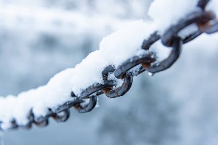 rusty iron chain hanging on a frost covered with snowの写真素材
