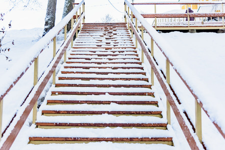 wooden staircase to the bottom in winter covered with snowの写真素材
