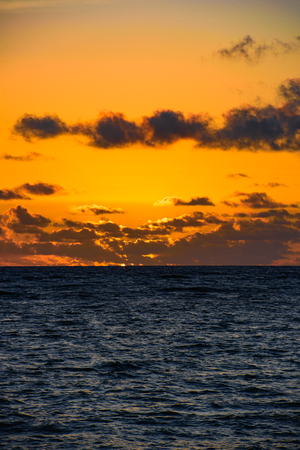 beautiful sunrise sun in the clouds on a quiet calm seaの写真素材