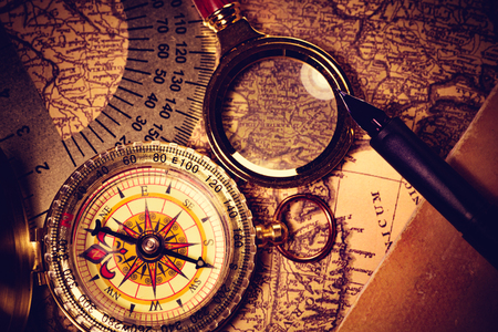 Old golden compass with magnifier and mapの写真素材