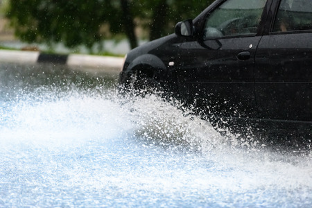 motion car rain big puddle of water spray from the wheelsの写真素材