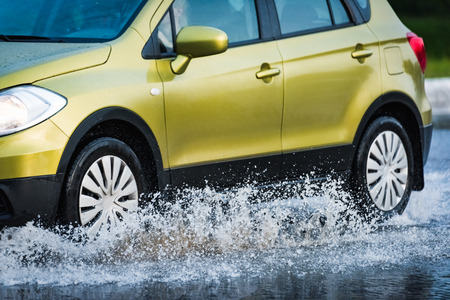 motion car rain big puddle of water spray from the wheelsの写真素材