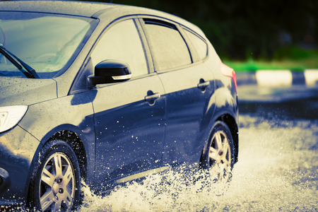 motion car rain big puddle of water spray from the wheelsの写真素材