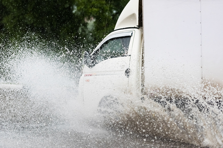 motion car rain big puddle of water spray from the wheelsの写真素材