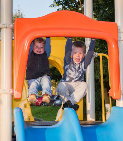 Senior and younger brothers ride the slides on the playgroundの写真素材