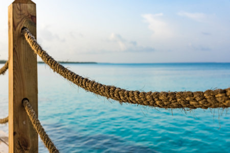 pier rope fence leaves in a sea of turquoise color close-up perspective
