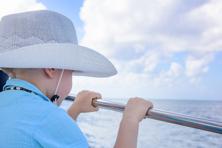 a little boy in a hat and shirt on a yacht in the open sea swimsの写真素材