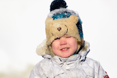 Portrait small child boy having fun wearing a padded jacket and knit hat while playing in the snow.の写真素材
