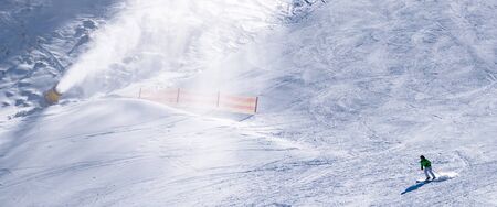 skier riding down the huge snowfield splashing powder snow.の写真素材