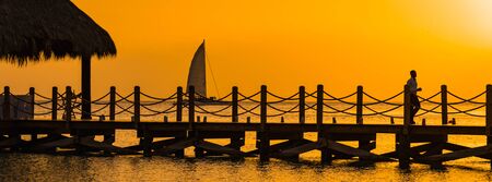 Wooden pier on the sea during sunset. Beautiful orange purple sk. Ies reflecting on the Caribbean Dominican Republicの写真素材