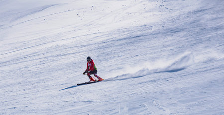 skier riding down the huge snowfield splashing powder snow.の写真素材