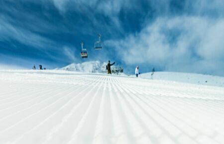 Chair ski lift for mountain skiers and snowboarders moves in the air on a rope on the background of winter snow capped mountains.の写真素材
