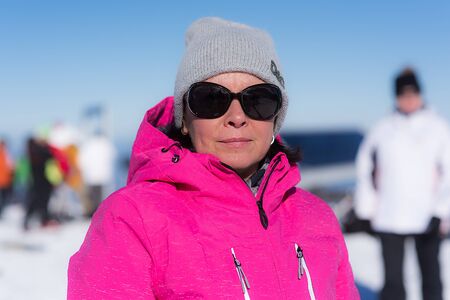 portrait of a middle-aged brunette in a white jacket with a hood on a background of mountainsの写真素材
