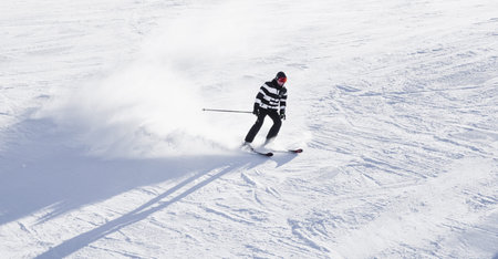 Bulgaria. Bansko. 14 February 2020.skier riding down the huge snowfield splashing powder snow.のeditorial素材
