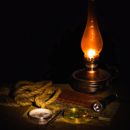 planning a trip at night at a table in the light of a kerosene lamp. Researching an old map with a...