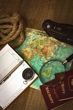 Preparing for an adventure trip. At night, inspection of an old map with a compass and a magnifier under the light of a lamp. Dark background.の写真素材