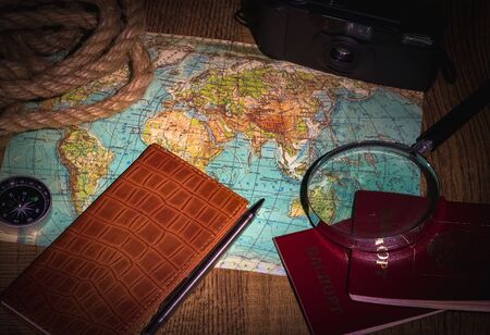 Preparing for an adventure trip. At night, inspection of an old map with a compass and a magnifier under the light of a lamp. Dark background.の写真素材