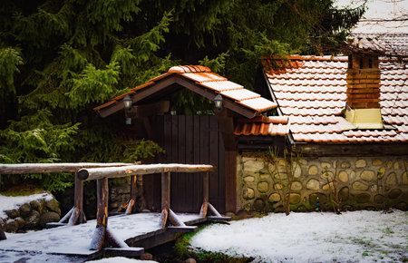 rustic winter landscape. entrance to the courtyard of an old house with a tiled roof with a brick...