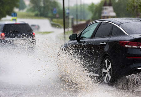 Russia. Moscow.May 30, 2020 . A car drives through a pool of water with splashes. Spring flood in the city.のeditorial素材