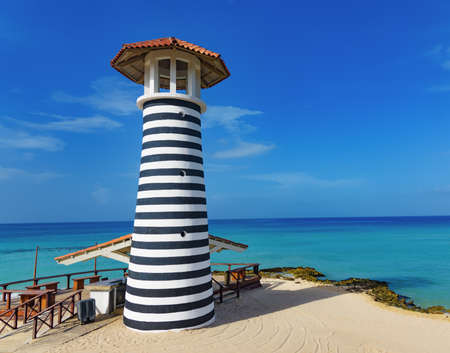 a striped high lighthouse stands on the shores of the Caribbean Dominican Republic for the safety of shipsの写真素材