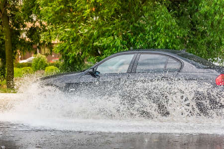 Russia. Moscow.May 30, 2020. A car drives through a pool of water with splashes. Spring flood in the city.のeditorial素材