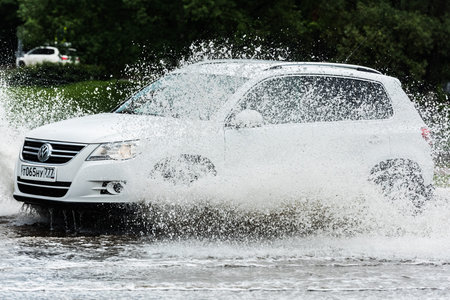 Russia. Moscow.May 30, 2020. A car drives through a pool of water with splashes. Spring flood in the...