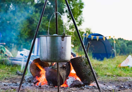 kettle on a tripod hanging around a bonfireの写真素材