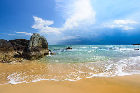 beautiful seascape landscape with sandy beach and big stonesの写真素材