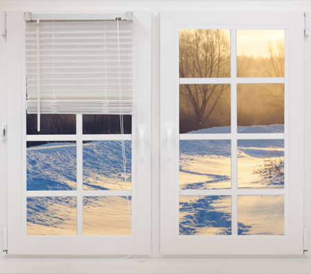 view through the frozen window on the winter landscape sun raysの写真素材