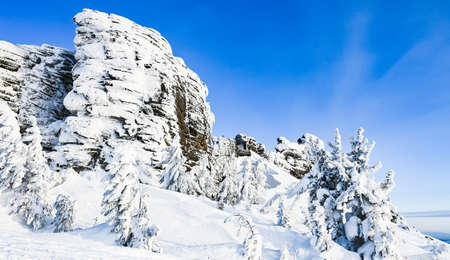 stone rock in winter frost covered with snow on blue sky backgroundの写真素材