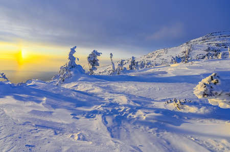 beautiful view of the sunset in winter from the top of a snowy hillの写真素材