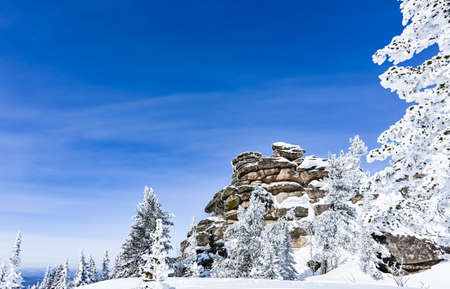 high stone cliff covered with snow in frosty sunny winterの写真素材