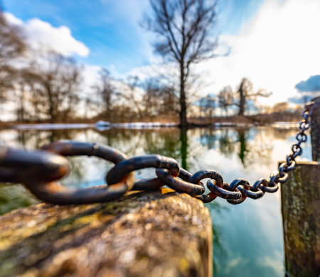 old wooden pier with iron chain and pillars on the lake