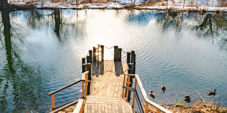 wooden bridge to the reservoir on a spring day in the water the reflection of the sunの写真素材