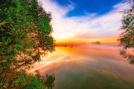 colorful calm dawn in the morning on the pond sun rays reflection in the waterの写真素材