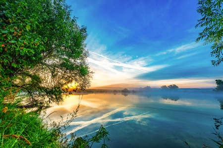 colorful calm dawn in the morning on the pond sun rays reflection in the waterの写真素材